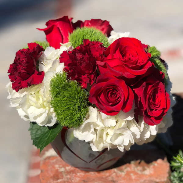 Red roses and white hydrangeas in a gray vase with green carnations