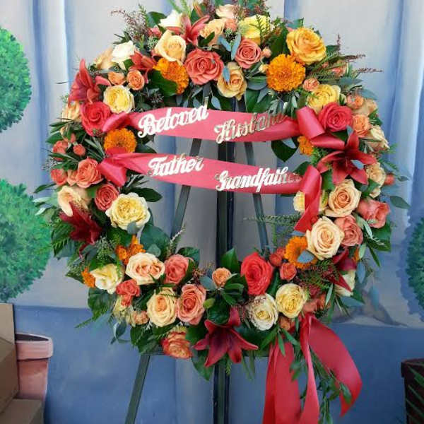 Large floral funeral wreath with roses and ribbons on an easel
