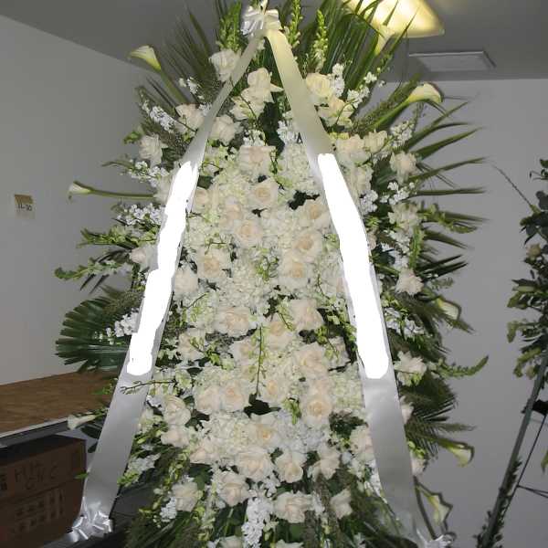 Large white funeral spray with roses and lilies on a standing easel