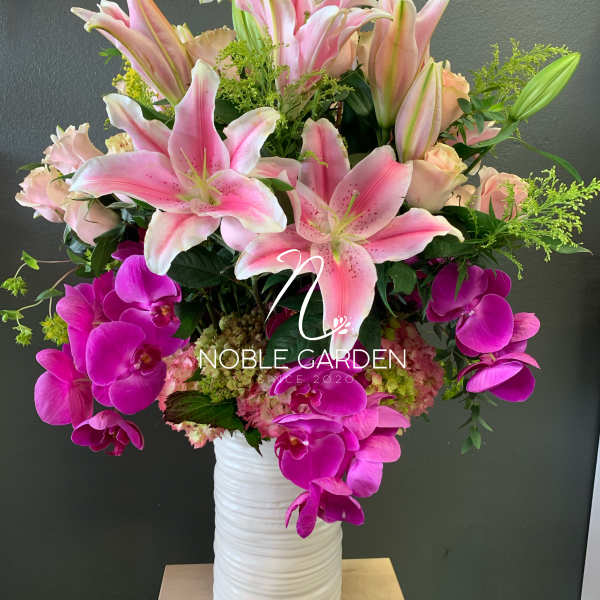 Pink lilies and magenta orchids in a white vase