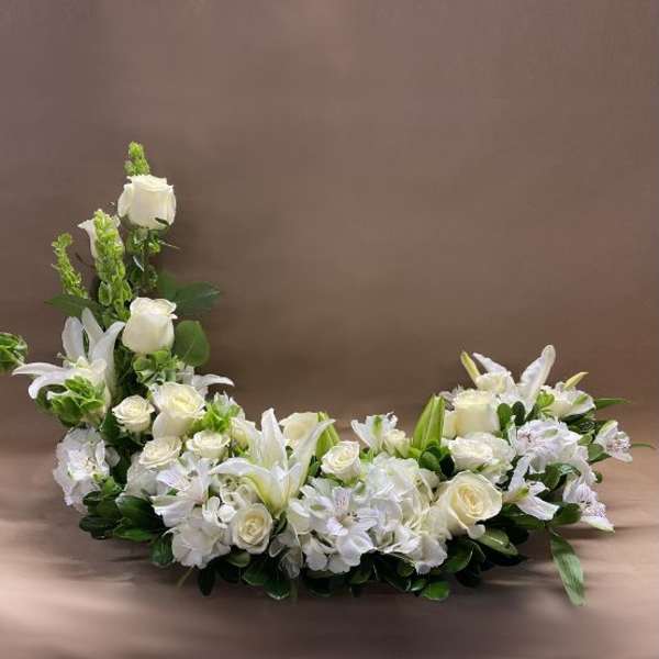 White floral casket spray with roses and lilies