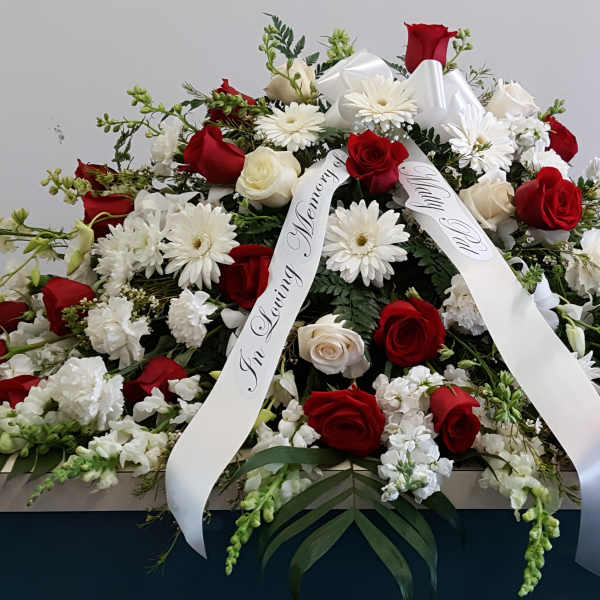 Casket spray of red and white roses with white daisies and ribbon
