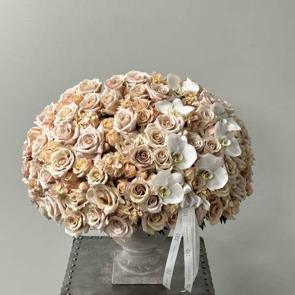 Large bouquet of blush roses and white orchids in a stone vase