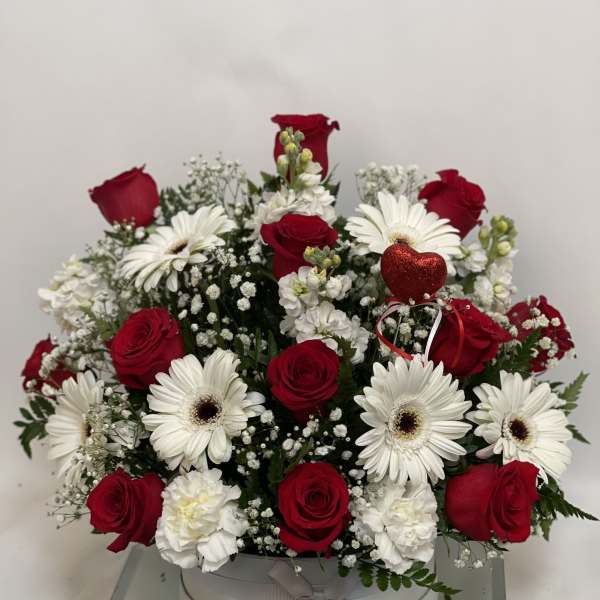Red roses and white gerbera daisies in a round white box with a red heart pick