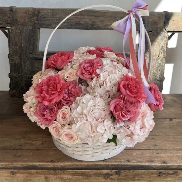 Basket of pink roses and pale hydrangeas with a ribbon handle