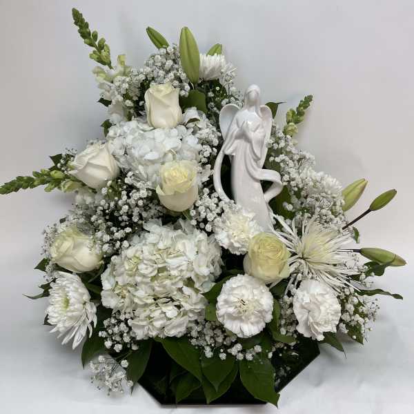 White floral arrangement with roses, lilies, and an angel figurine