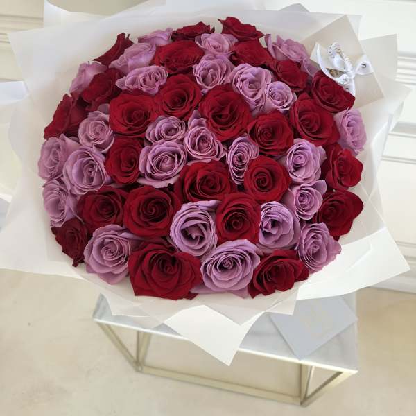 Bouquet of red and lavender roses wrapped in white paper