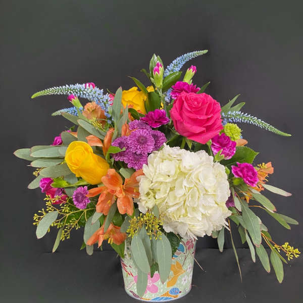 Colorful mixed bouquet in a patterned tin container
