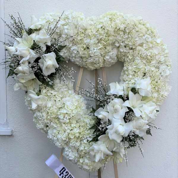 White floral heart wreath on an easel with ribbon