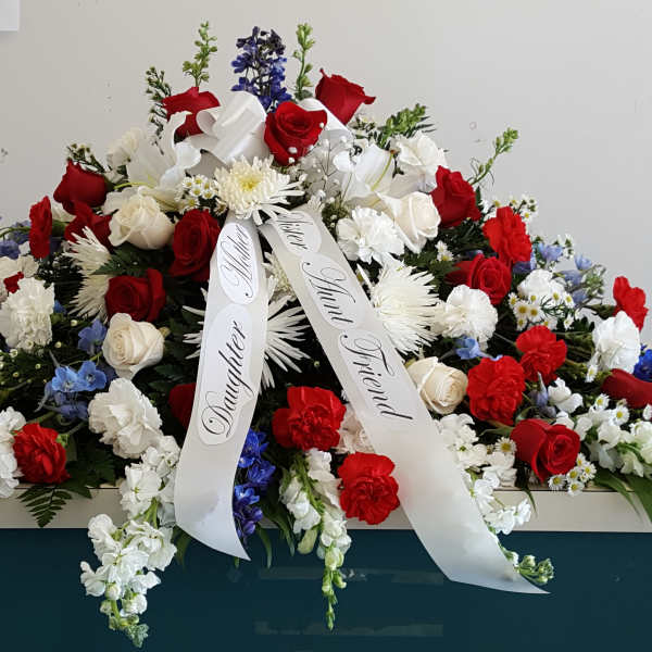 Large red, white, and blue funeral spray with ribbon streamers