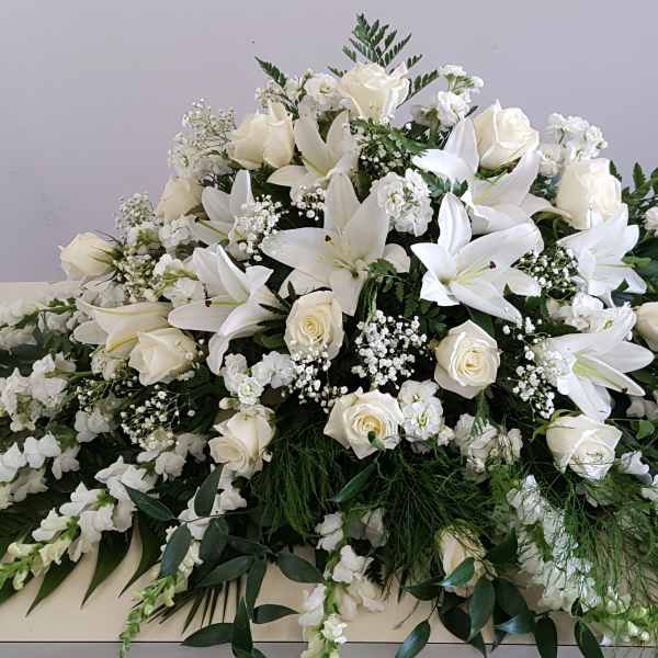 Large white floral spray with lilies and roses on a table