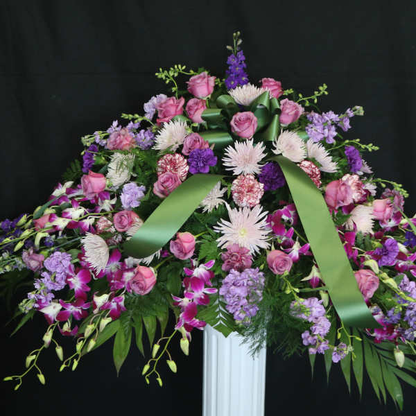 Large floral spray with pink roses and purple flowers on a stand