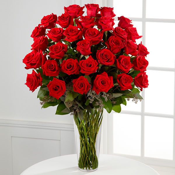 Tall bouquet of red roses in a clear glass vase