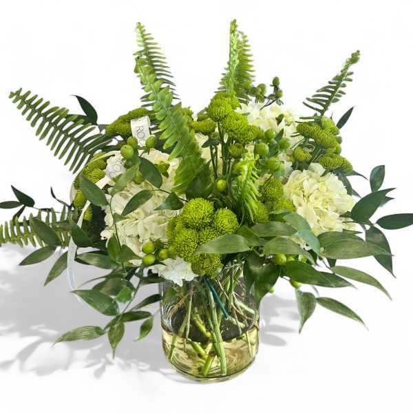 Green and white floral arrangement in a glass vase