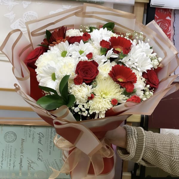 Bouquet of red and white flowers wrapped in translucent paper