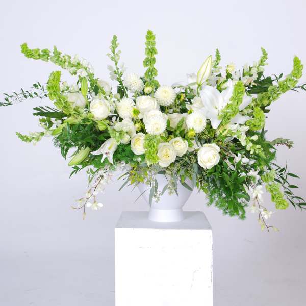 White floral arrangement in a white pedestal vase