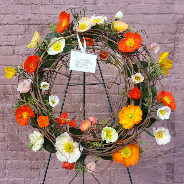 Circular wreath of orange, white, and yellow flowers on a stand