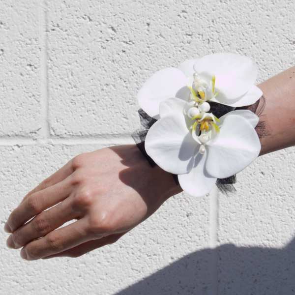 White orchid wrist corsage with black tulle on a person's wrist