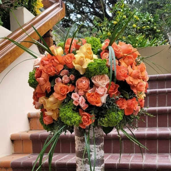 Large bouquet of orange and peach roses in a birch-style vase