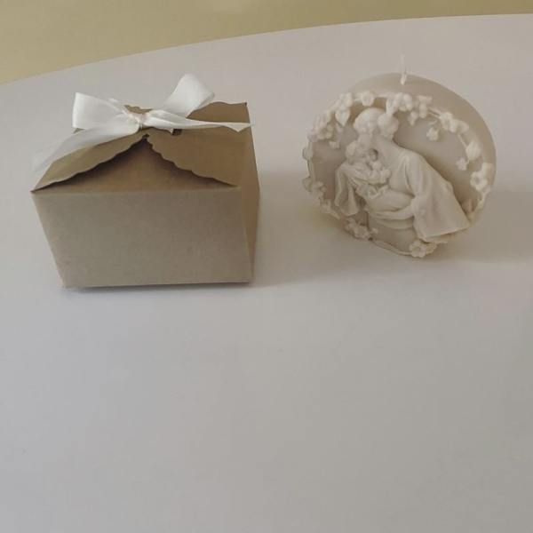 A small kraft gift box with a white ribbon beside a white decorative figurine.