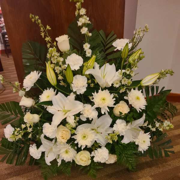 Large white floral arrangement with lilies, roses, and daisies