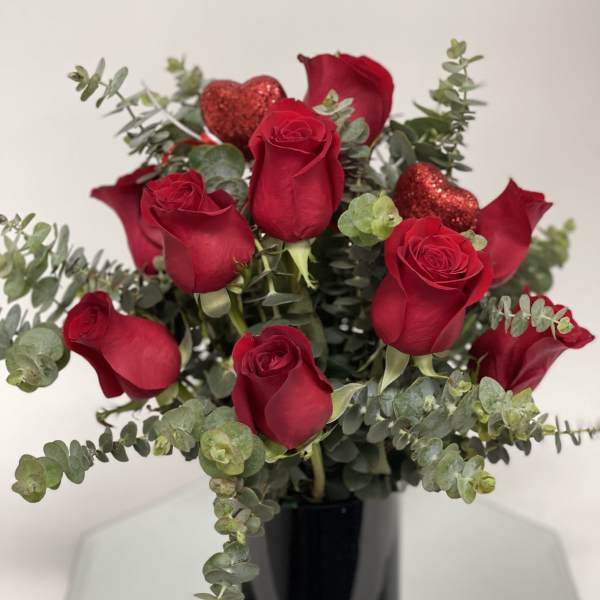Red roses with eucalyptus in a black vase