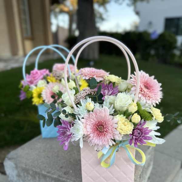 Pastel flower arrangement in a pink gift bag with ribbon handles
