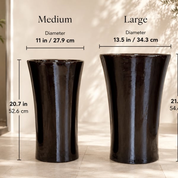 Two dark ceramic pedestal vases with size labels on a showroom wall.