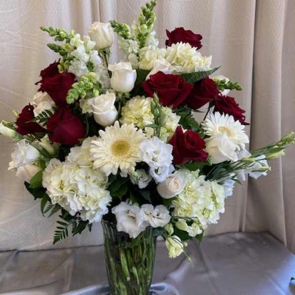 Red and white roses with white daisies in a glass vase