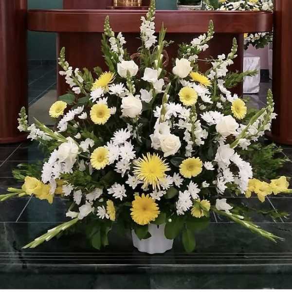 Large white and yellow floral arrangement in a white container