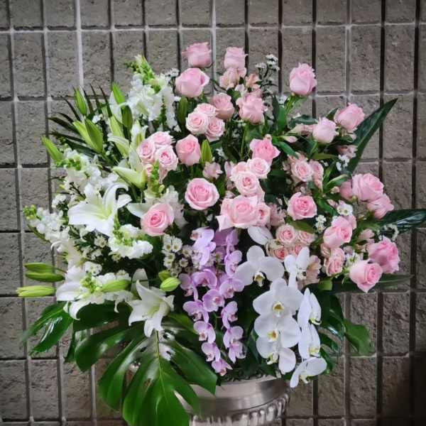 Large pink and white floral arrangement in a silver urn vase