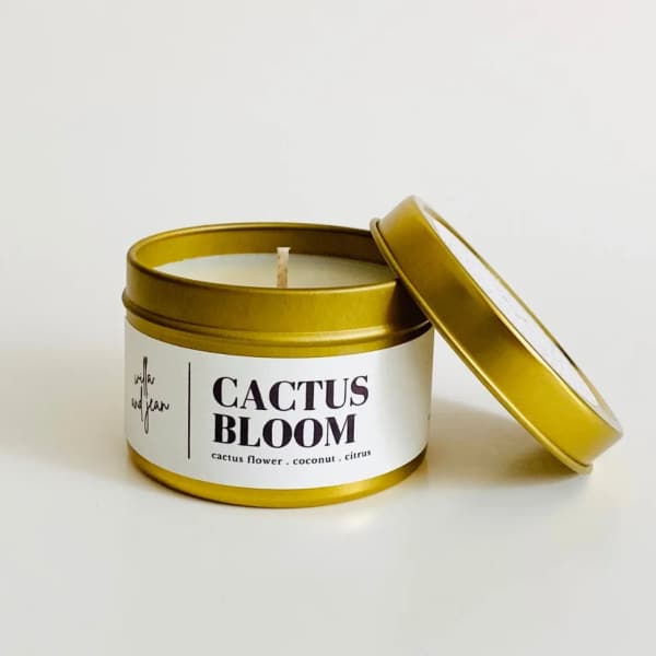 Gold tin candle labeled Cactus Bloom with lid beside it