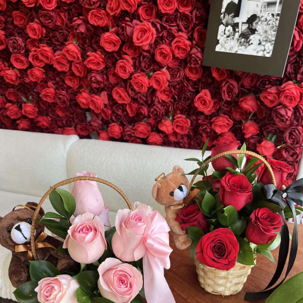 Two small rose baskets with teddy bears and ribbons on a table