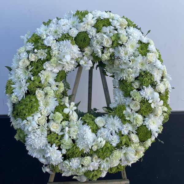 Large white and green floral wreath on an easel