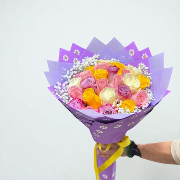 Handheld bouquet of multicolored roses wrapped in purple paper