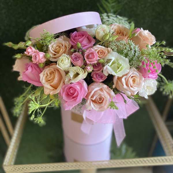 Pink and peach roses arranged in a pale pink hatbox