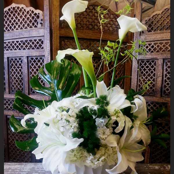 White calla lilies and lilies arranged in a white vase