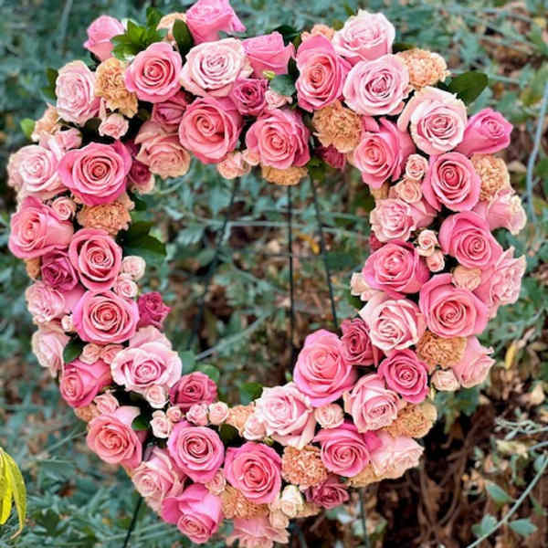 Heart-shaped arrangement of pink roses and spray roses