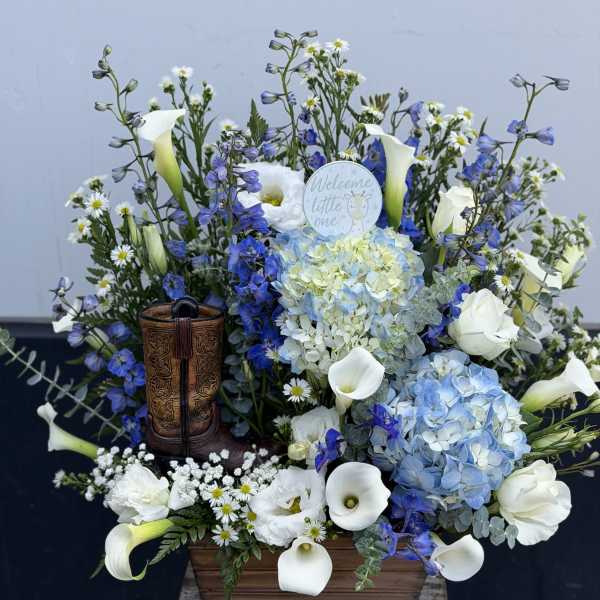 Blue and white floral arrangement with calla lilies and hydrangeas in a wooden container