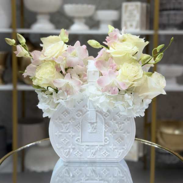 White floral arrangement in a decorative white handbag-shaped vase