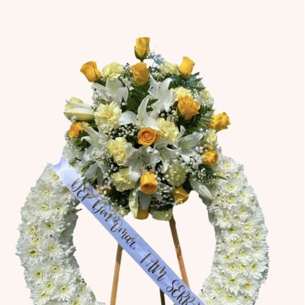 White floral funeral wreath with yellow roses and a ribbon on an easel