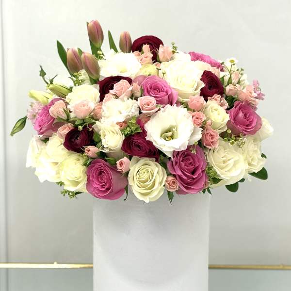 Mixed pink, white, and burgundy flowers arranged in a white box