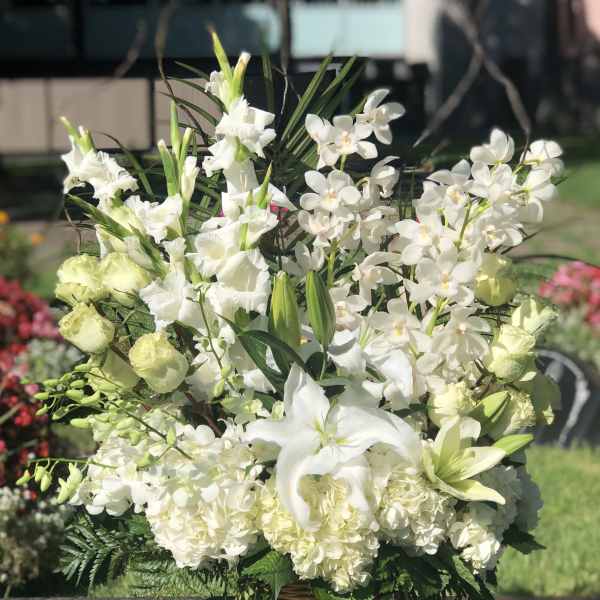 White lilies and orchids arranged in a wicker basket