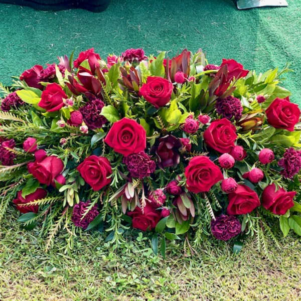 Large red rose and burgundy floral spray on the ground