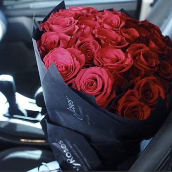 Bouquet of red roses wrapped in dark paper