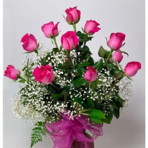 Pink roses in a vase with baby's breath and a pink ribbon