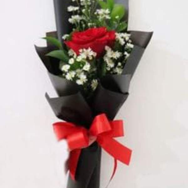 Red rose bouquet with white filler flowers wrapped in black paper and tied with a red bow
