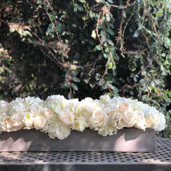 Low floral arrangement of white and blush roses in a rectangular container