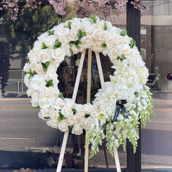 Large white floral wreath on a wooden easel with cascading flowers