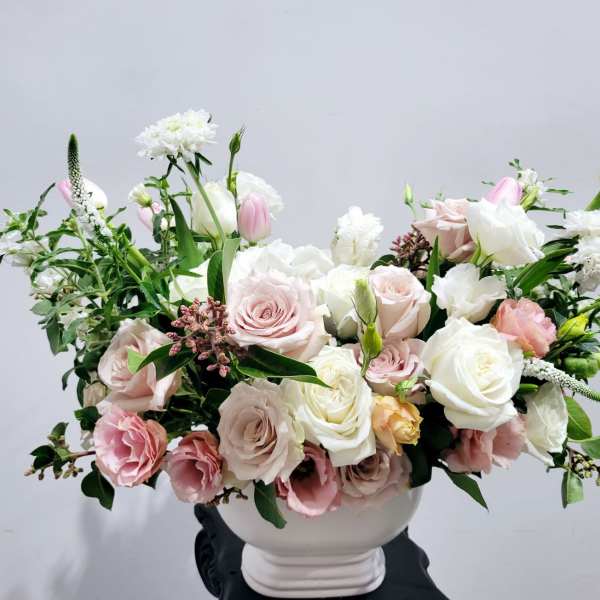 Pink and white rose arrangement in a white vase